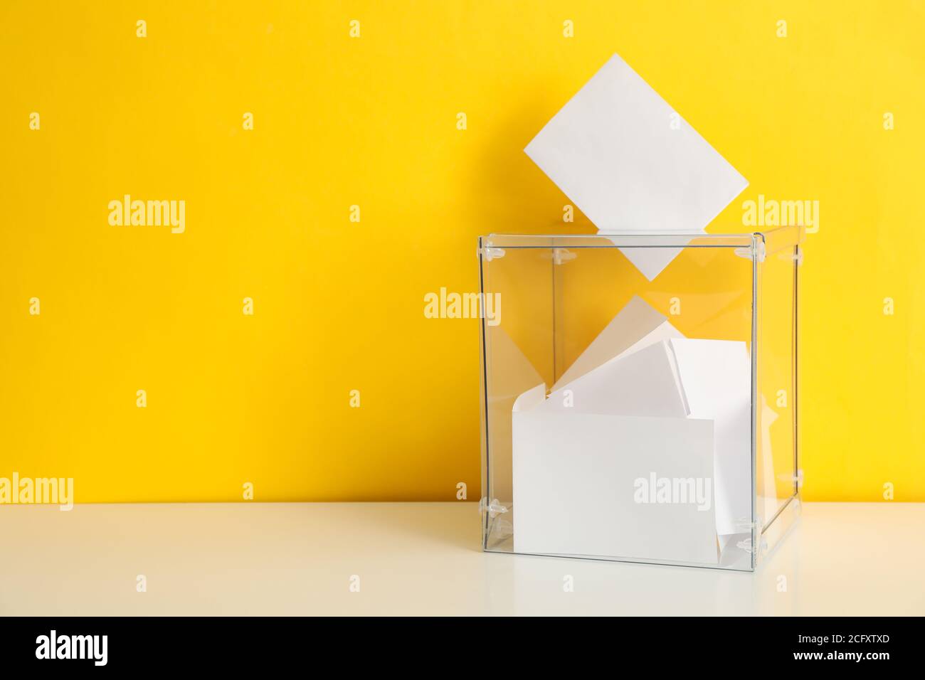 Casella di votazione con i bollettini su sfondo giallo, spazio per il testo Foto Stock