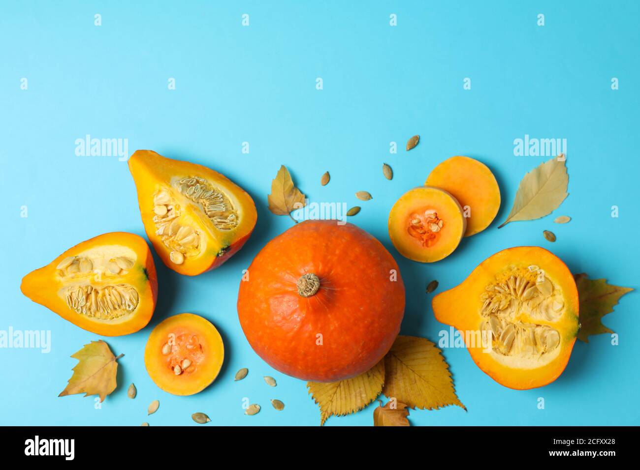 Fette di zucca, foglie e semi su blu, una composizione audace di Halloween per ottobre Foto Stock