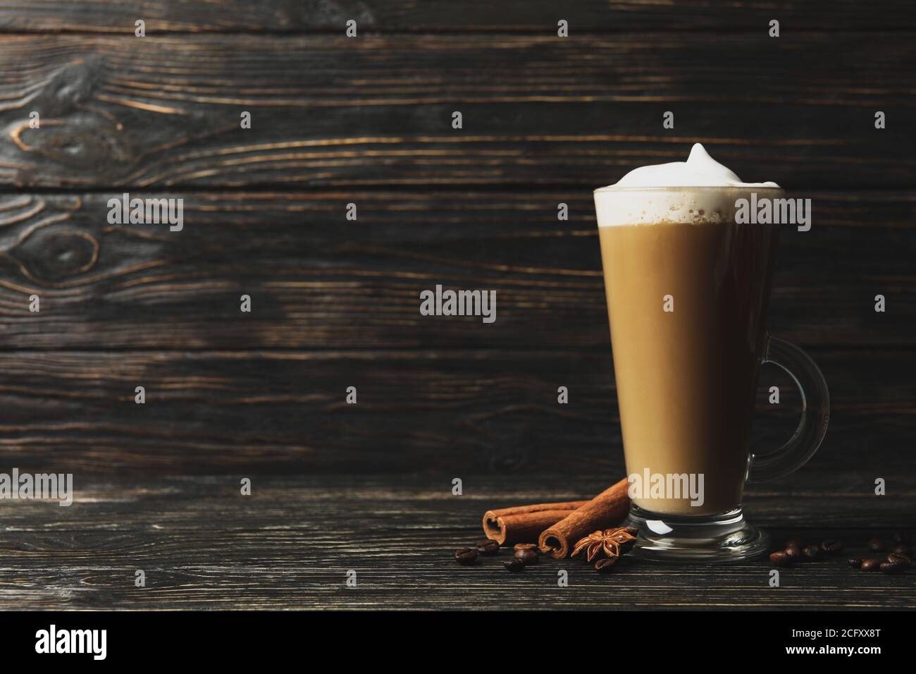 Bicchiere di latte, semi di caffè e cannella su fondo di legno Foto Stock