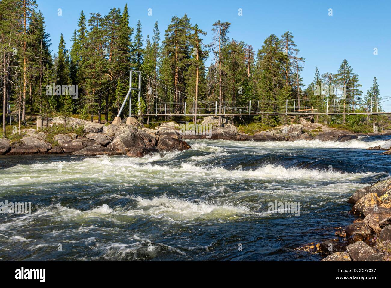 Parte del ponte sospeso sopra Trollforsen rapido nel fiume Pite nel nord della Svezia con acqua corrente sotto e foresta sullo sfondo. Foto Stock