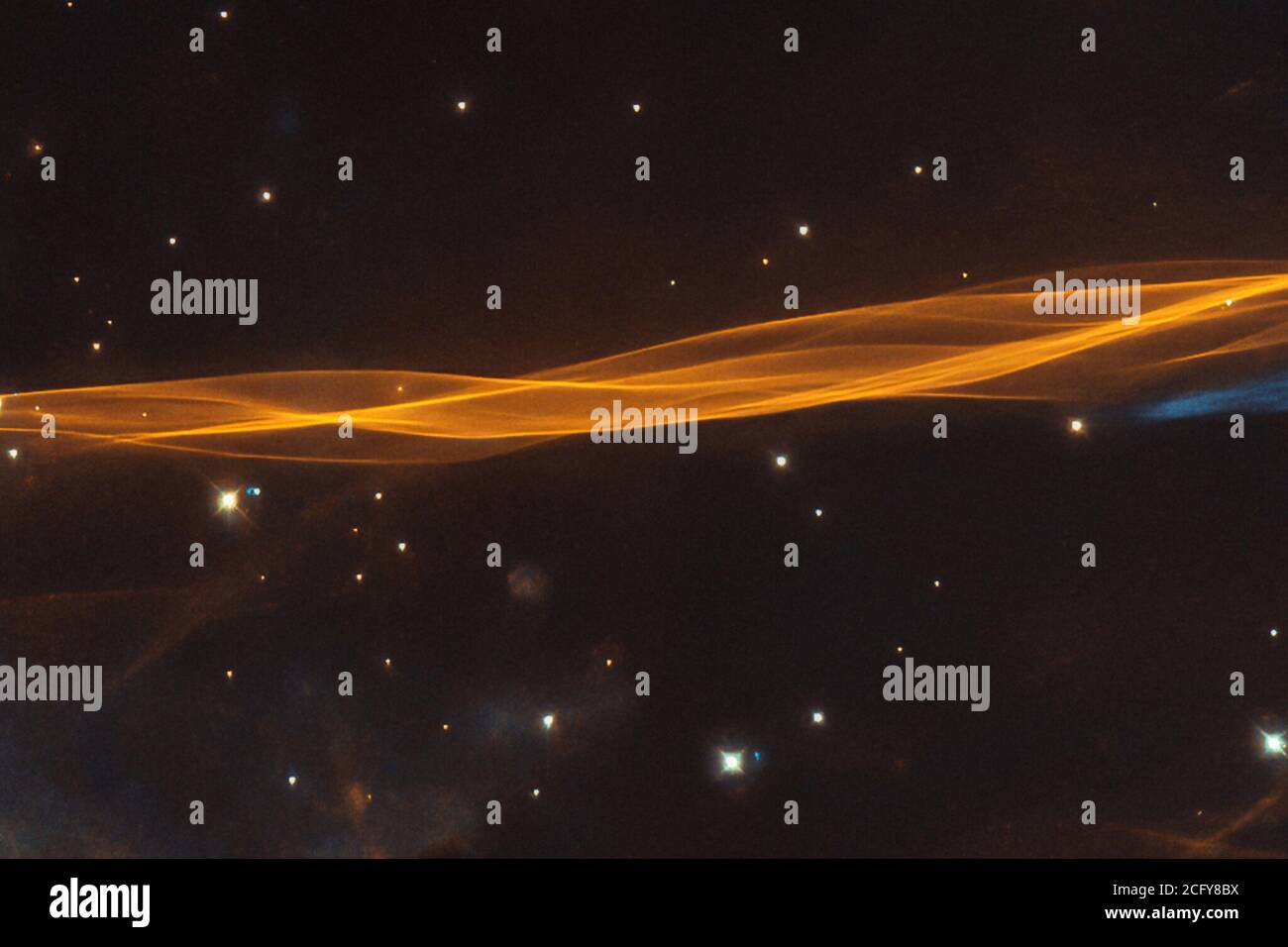 Mentre si presenta come un velo delicato e leggero drappeggiato attraverso il cielo, questa immagine dal telescopio spaziale NASA/ESA Hubble raffigura in realtà una piccola sezione dell'onda d'esplosione della supernova Cygnus, situata a circa 2,400 anni di luce. Il nome del residuo della supernova deriva dalla sua posizione nella costellazione settentrionale di Cigno, dove copre un'area 36 volte più grande della Luna piena. L'esplosione originale della supernova ha fatto esplodere una stella morente circa 20 volte più massiccia del nostro Sole tra 10,000 e 20,000 anni fa. Da allora, il resto ha ampliato 60 anni luce dal suo cen Foto Stock