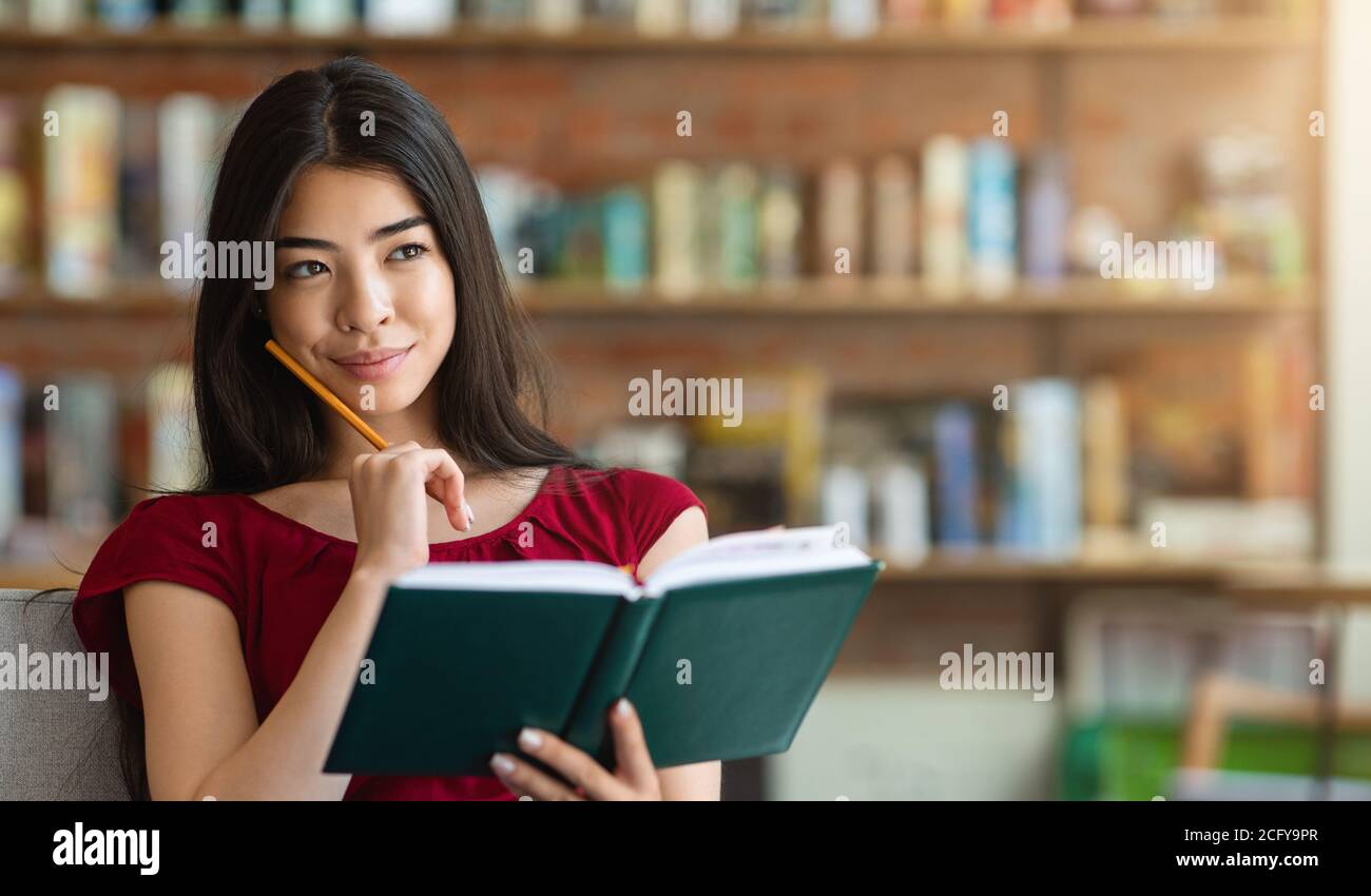 Pensare ai piani futuri. Pessive Asian Girl seduta con blocco note al Cafe Foto Stock