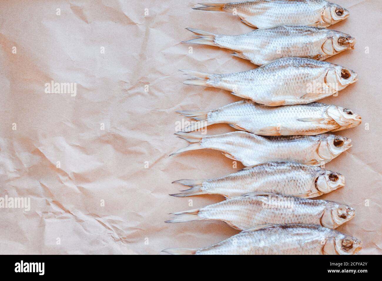 Banner modello pesci secchi su sfondo di carta artigianale con spazio vuoto per il testo. Rivestimento piatto in rete di roach salato. Poster per spuntini di pesce, dépliant decorativo. Cornice di pesce per il negozio di promozione. Foto Stock