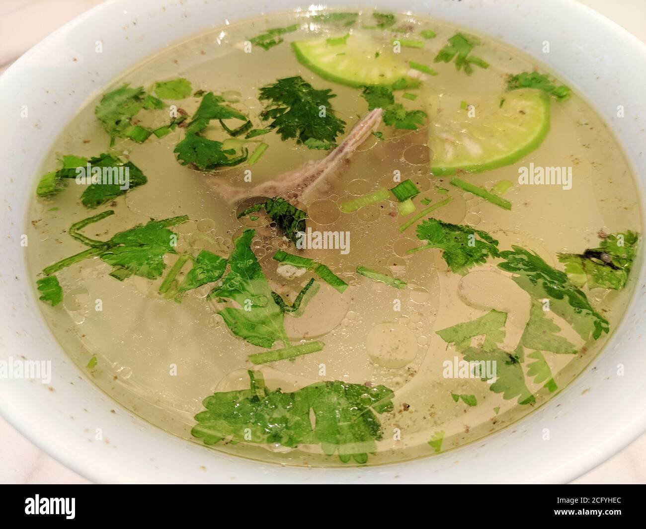 zuppa di agnello con verdure verdi in ciotola bianca sotto brillante leggero Foto Stock