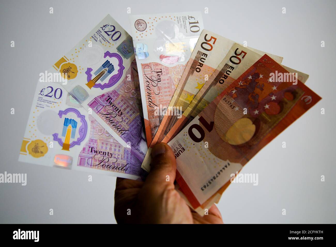In questa illustrazione fotografica, una persona detiene una collezione di banconote inglesi da dieci e venti sterline e dieci e cinquanta euro. Foto Stock