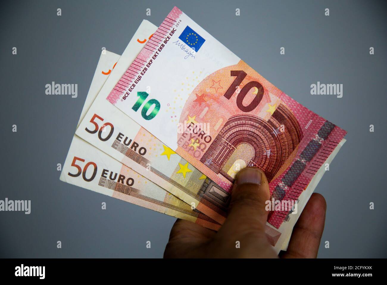 In questa illustrazione fotografica, una persona detiene una raccolta di dieci e cinquanta banconote in euro. Foto Stock