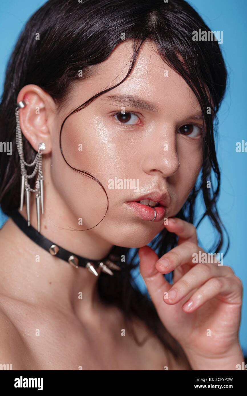 Ritratto di bella donna gotica con piercing e altri accessori in studio su sfondo bue. Emotivo, volto giovane. Emozioni umane, exp facciale Foto Stock
