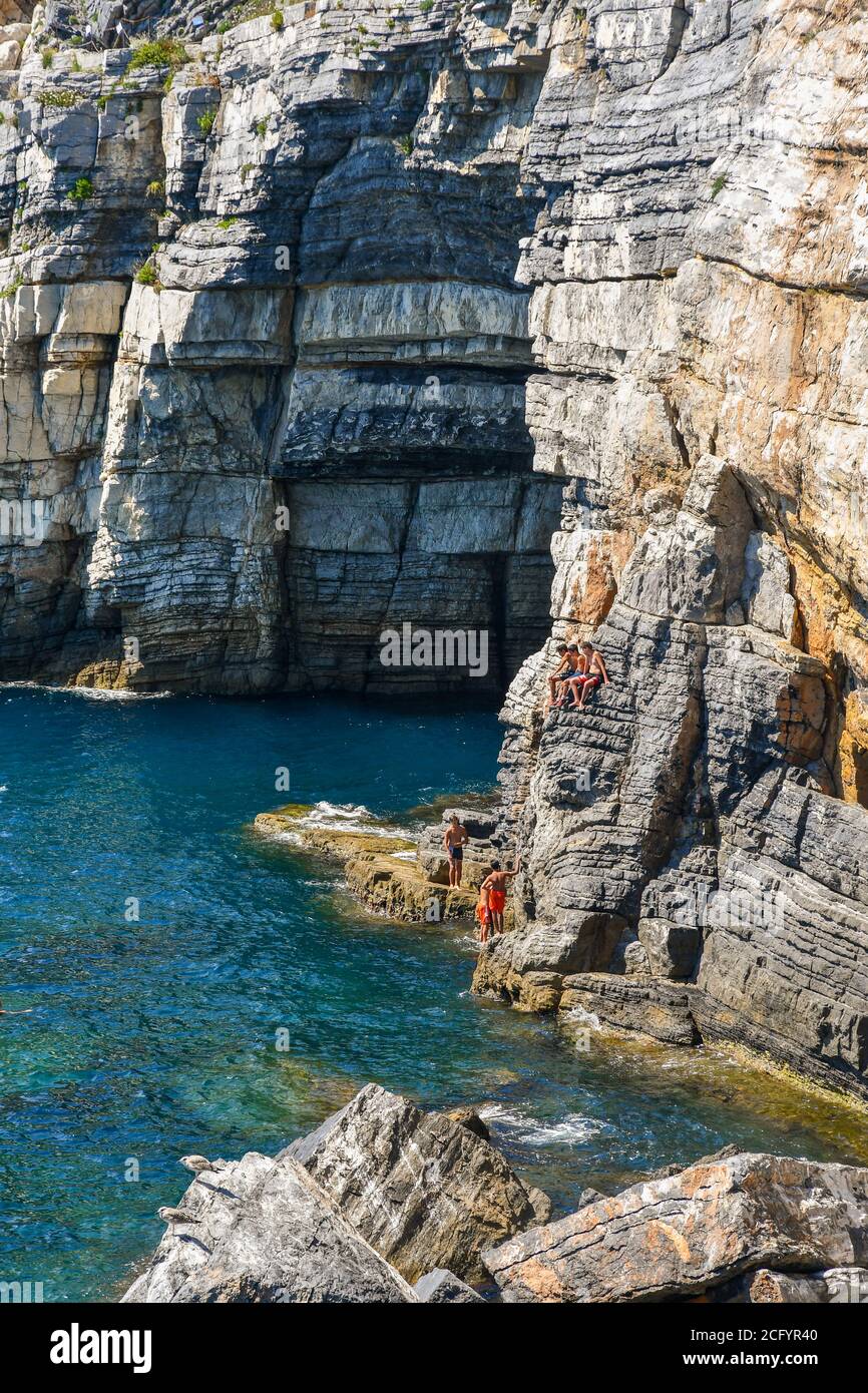 Un gruppo di adolescenti sulle rocce accanto alla Grotta del Signore Byron in una soleggiata giornata estiva, Porto Venere, la Spezia, Liguria, Italia Foto Stock