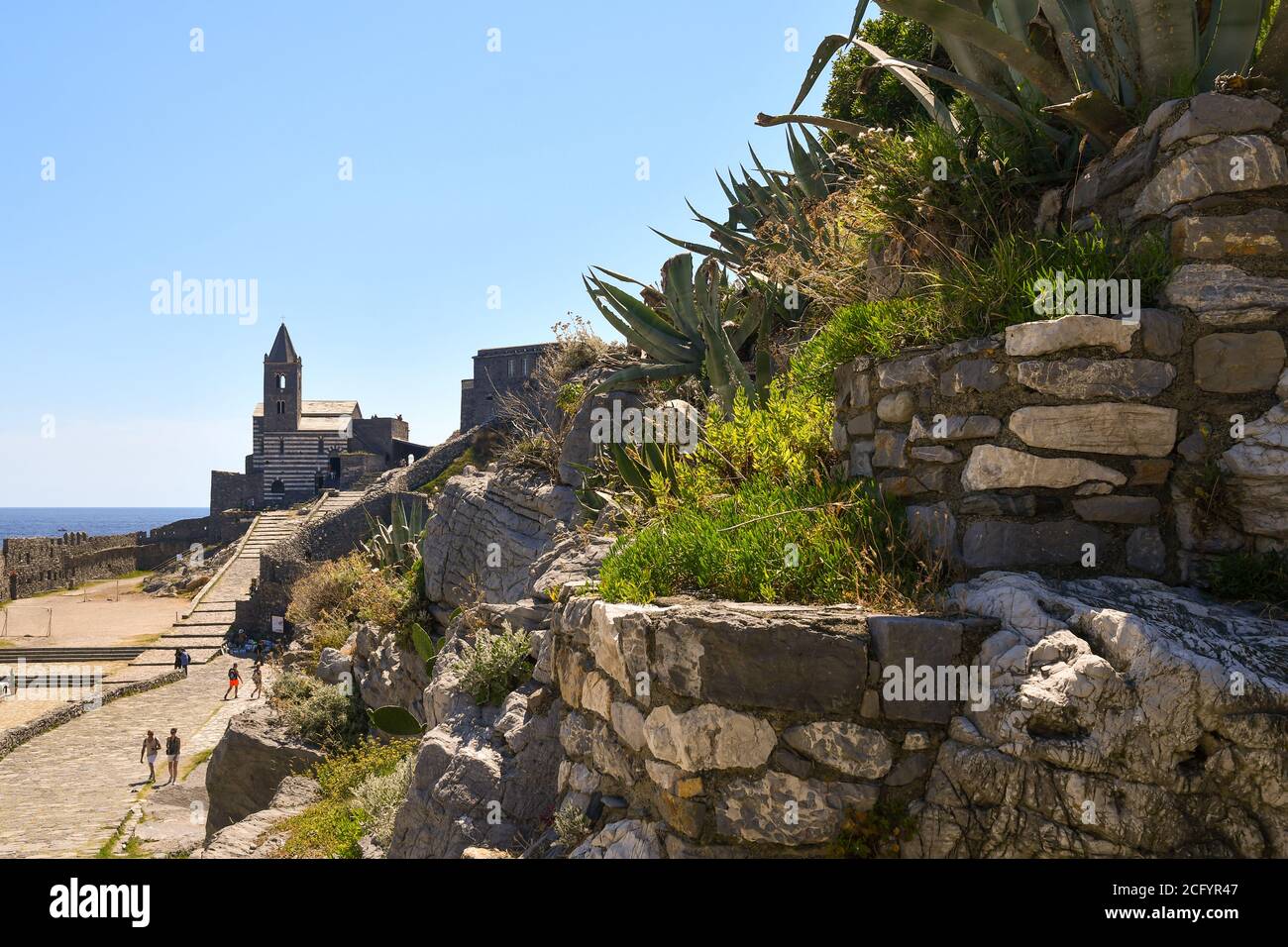 Le mura della città del villaggio di pescatori, patrimonio dell'umanità dell'UNESCO, con la famosa Chiesa di San Pietro e turisti, Porto Venere, la Spezia, Italia Foto Stock