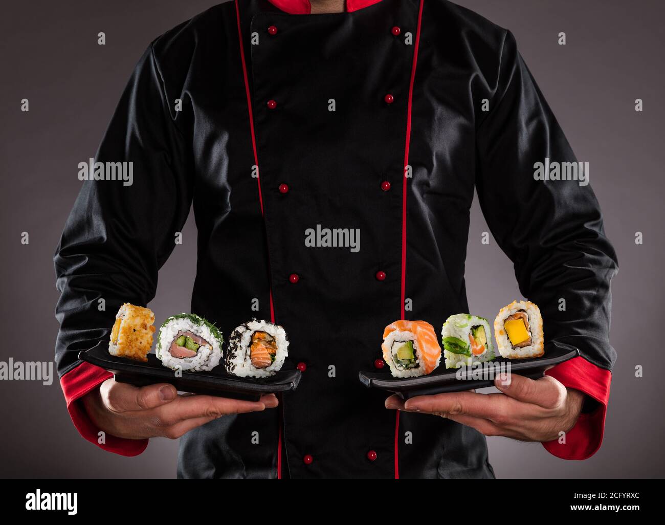 Primo piano del maestro chef che tiene piatti con pezzi di sushi. Concetto di cibo asiatico Foto Stock