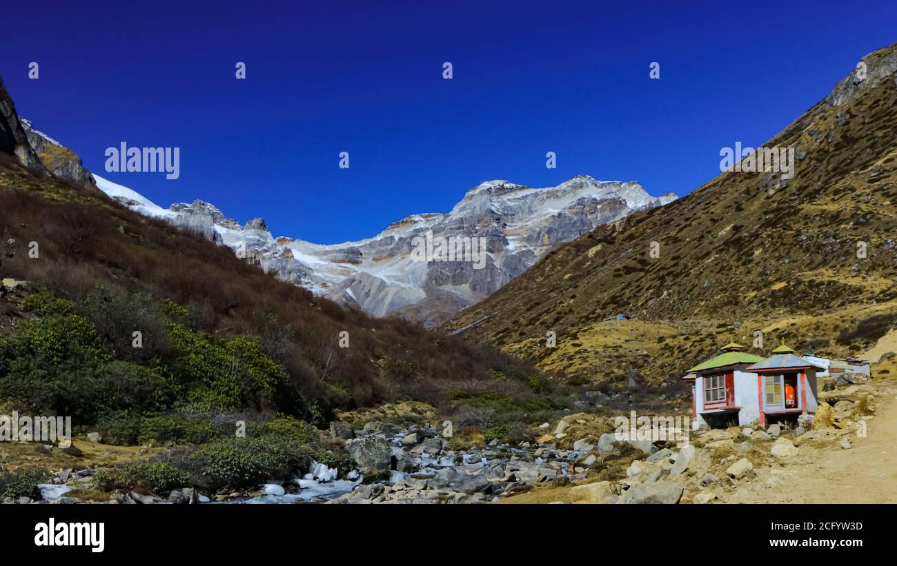 Immagine di messa a fuoco selettiva di una vista di una valle con capanna piccola e cime innevate nel lontano a. Nord Sikkim in India Foto Stock