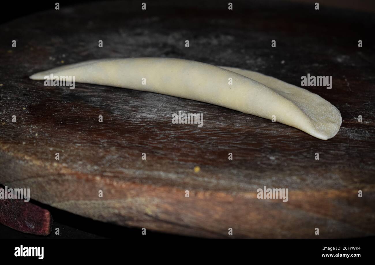 Poori dolci indiani crudi a base di farina raffinata e frutta secca ripieni all'interno conservati su un tavolo di legno. Foto Stock