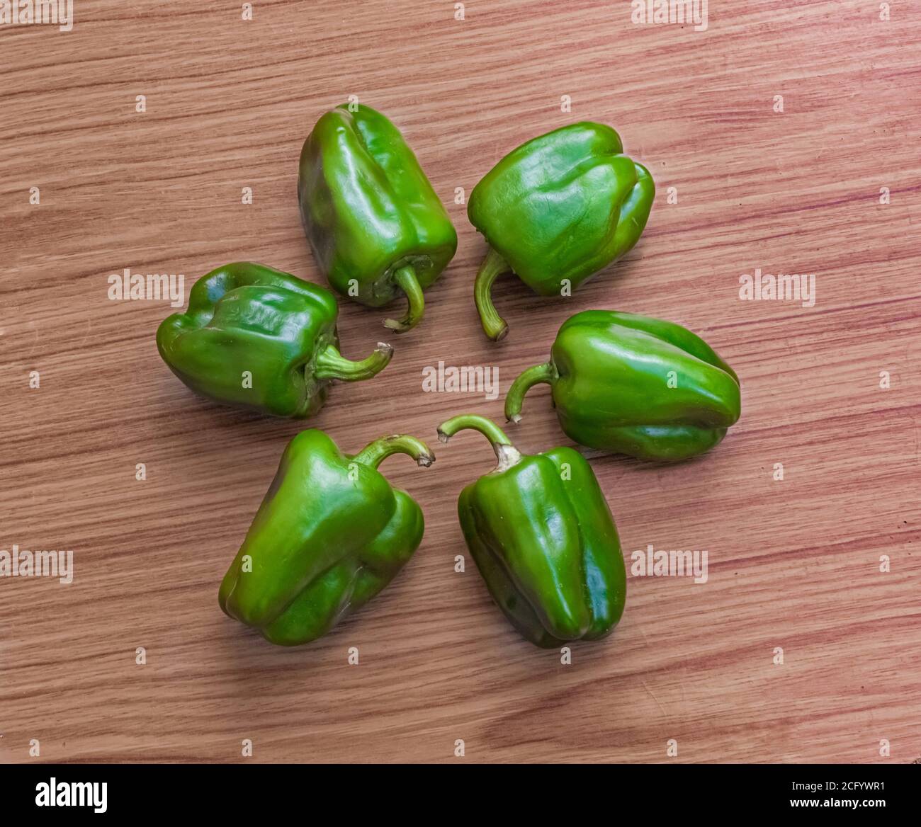 Inquadratura ad angolo superiore di sei cappicum tenuti su un tavolo di legno in una disposizione circolare. Foto Stock