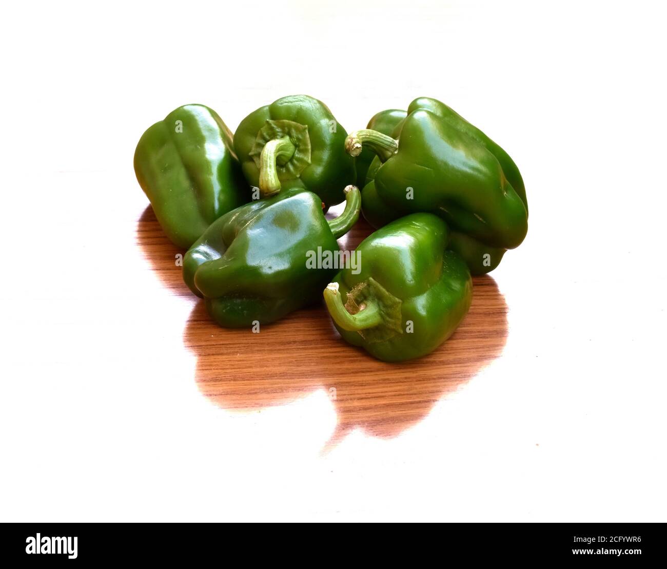 Gruppo di capsicums e la loro tessitura di legno d'ombra isolato su bianco. Foto Stock