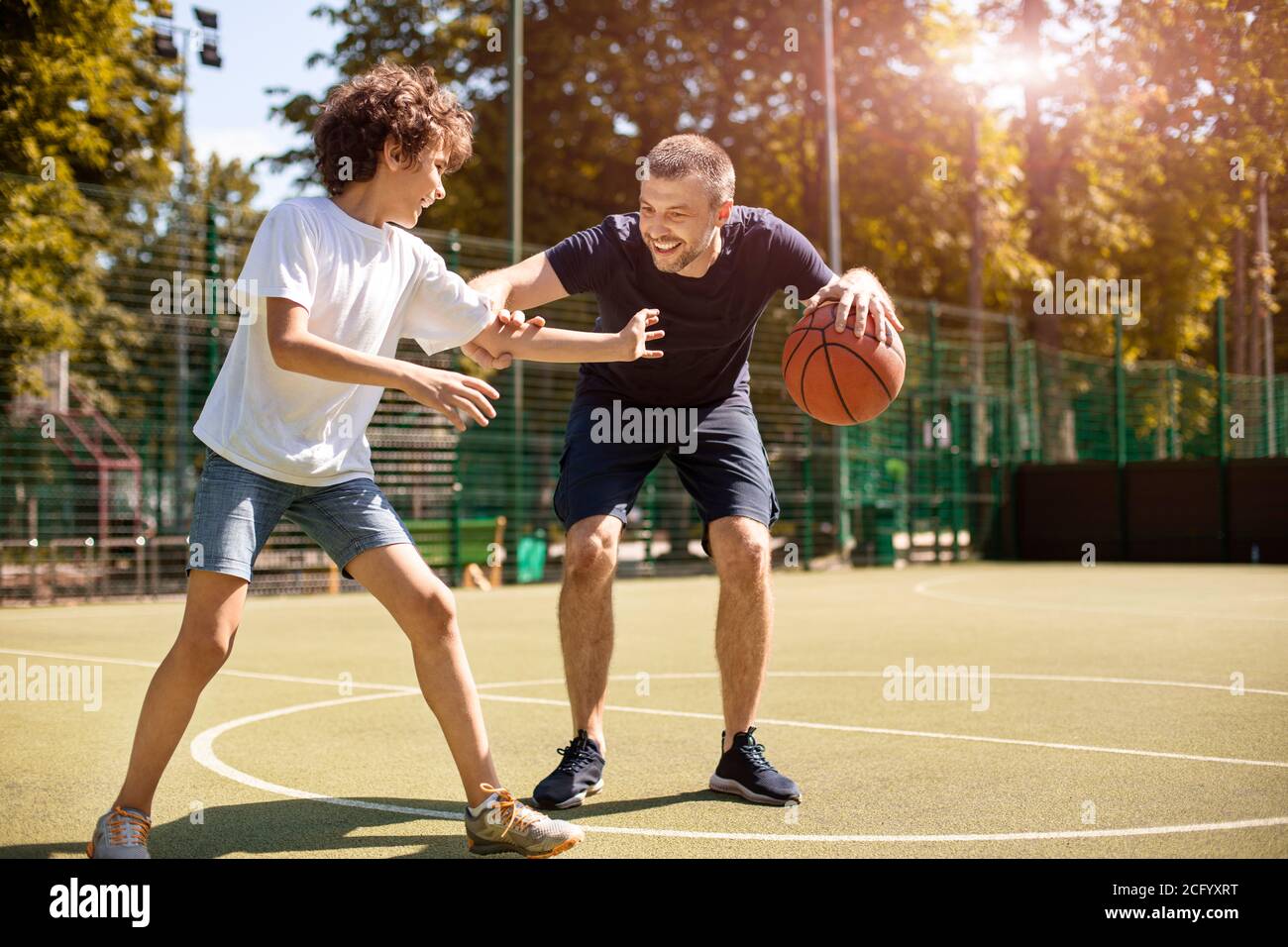 Uomo maturo insegnando ragazzo a giocare a basket Foto Stock