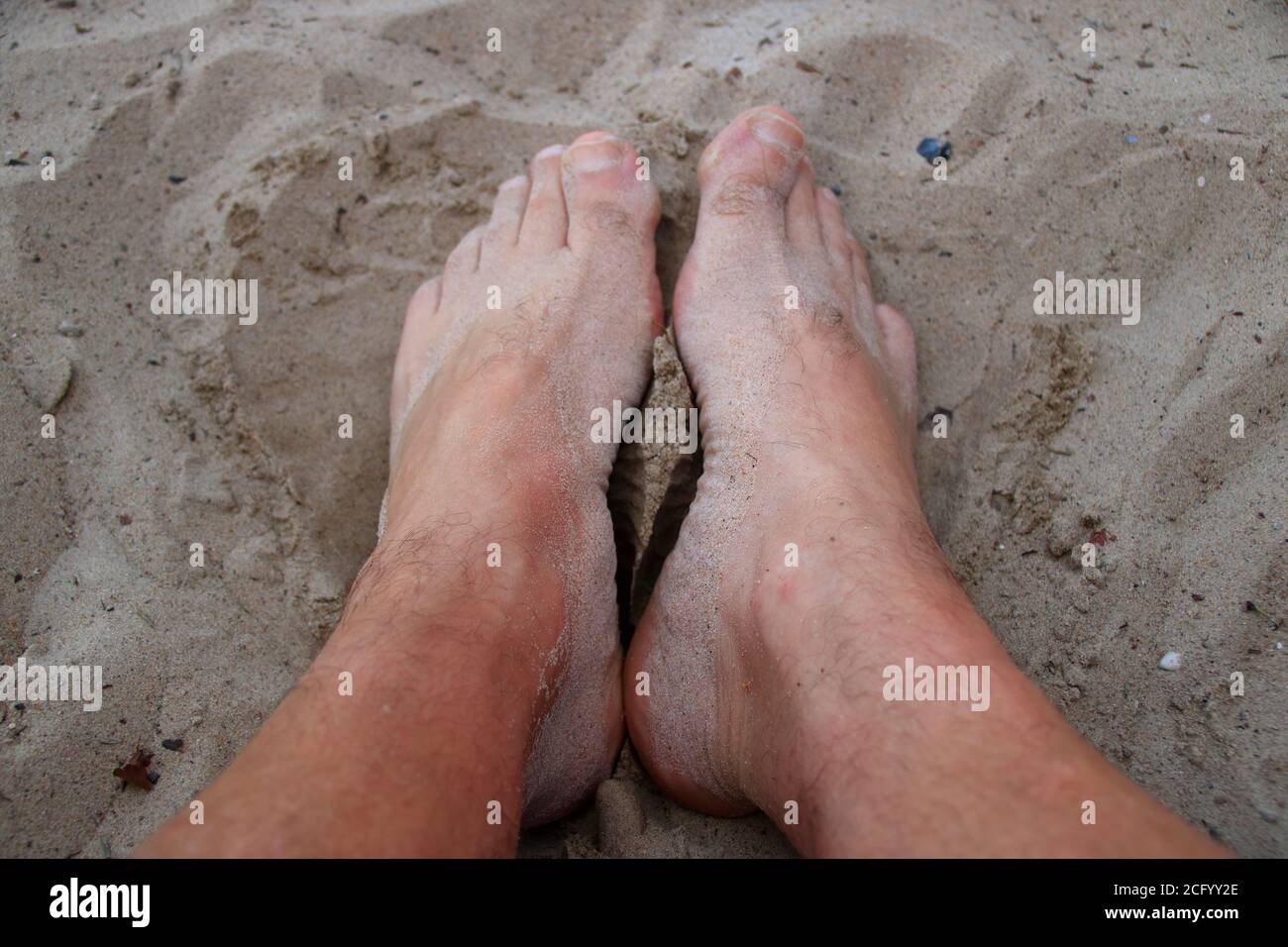 I piedi su una spiaggia di sabbia sono coperti di sabbia Foto Stock