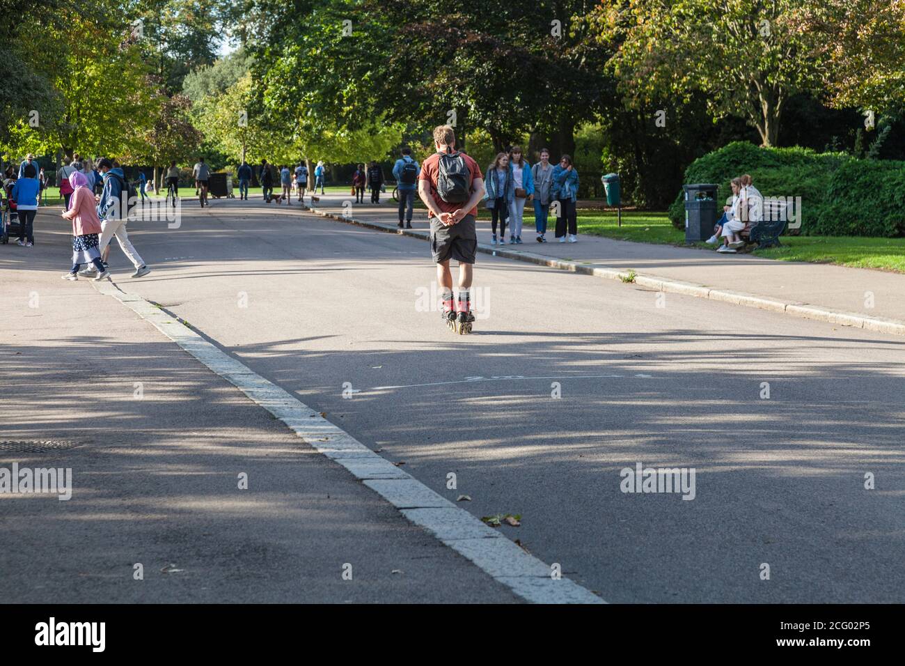 Un uomo che si diverta con un pattinatore attraverso la trafficata Victoria Parcheggia in un pomeriggio soleggiato a Londra, Inghilterra, Regno Unito Foto Stock