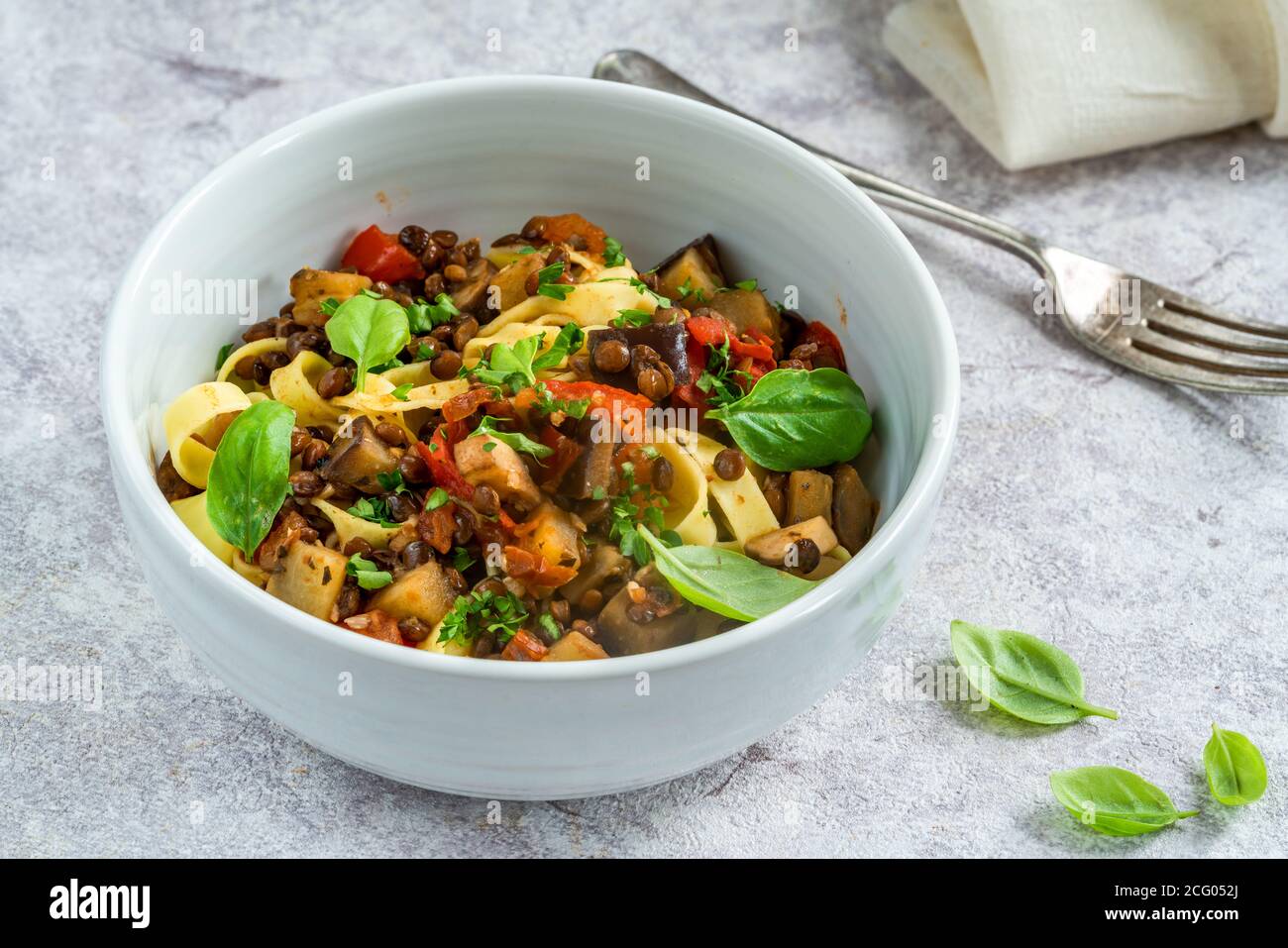 Lenticchie e melanzane ragu con tagliatelle e basilico fresco - cibo vegetariano sano Foto Stock
