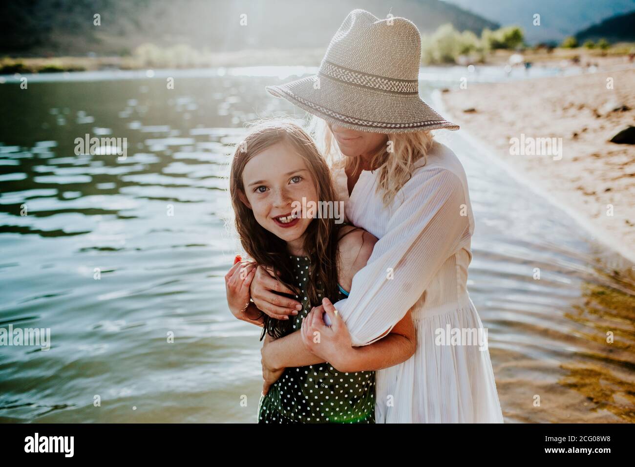 Mamma e figlia abbracciano e sorridono mentre si levano in piedi in un lago Foto Stock