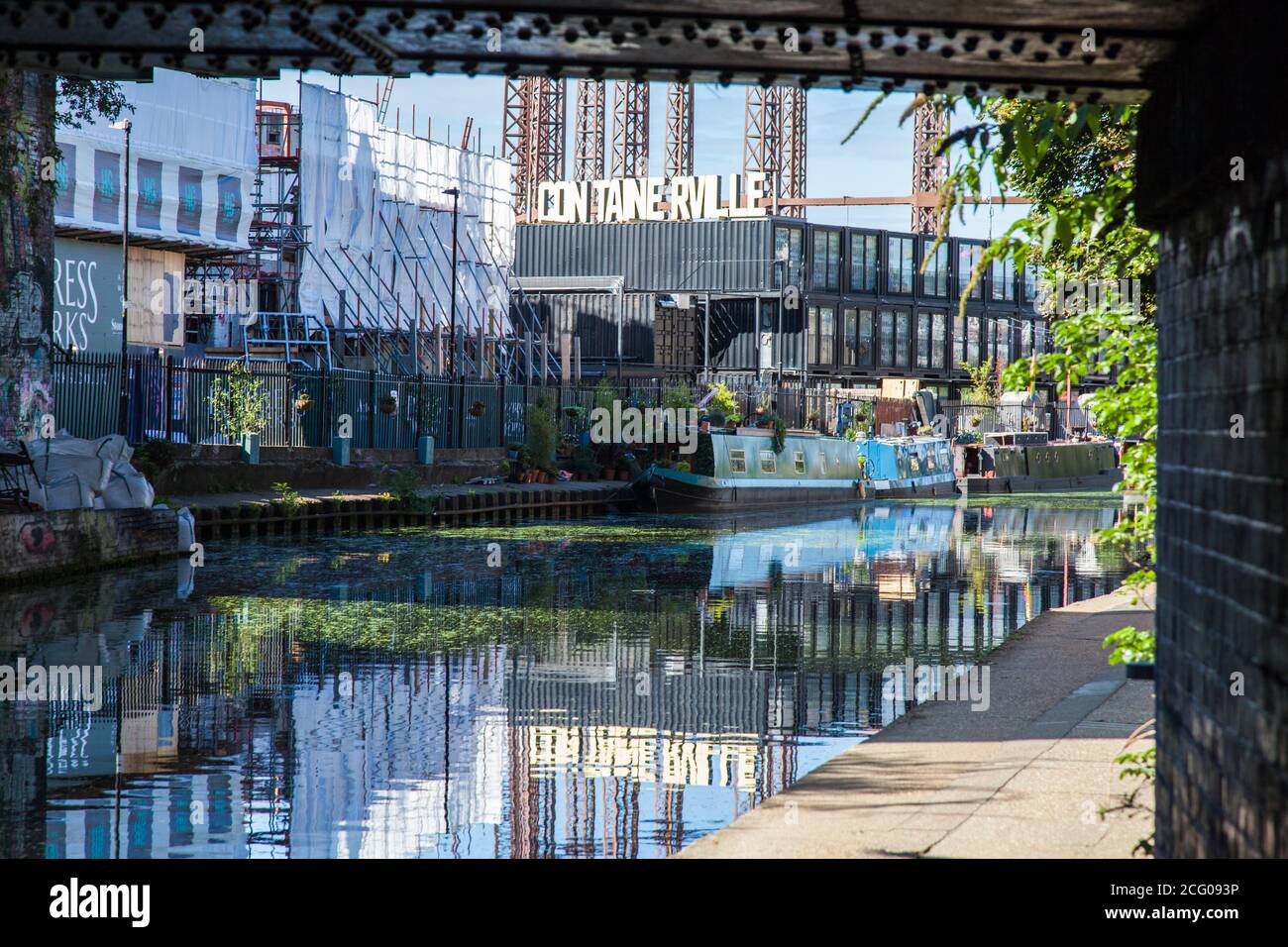 Regents Canal a Londra, Regno Unito, con le barche ormeggiate sul canale e i locali di Contaaperville sullo sfondo che gettano i riflessi sull'acqua Foto Stock