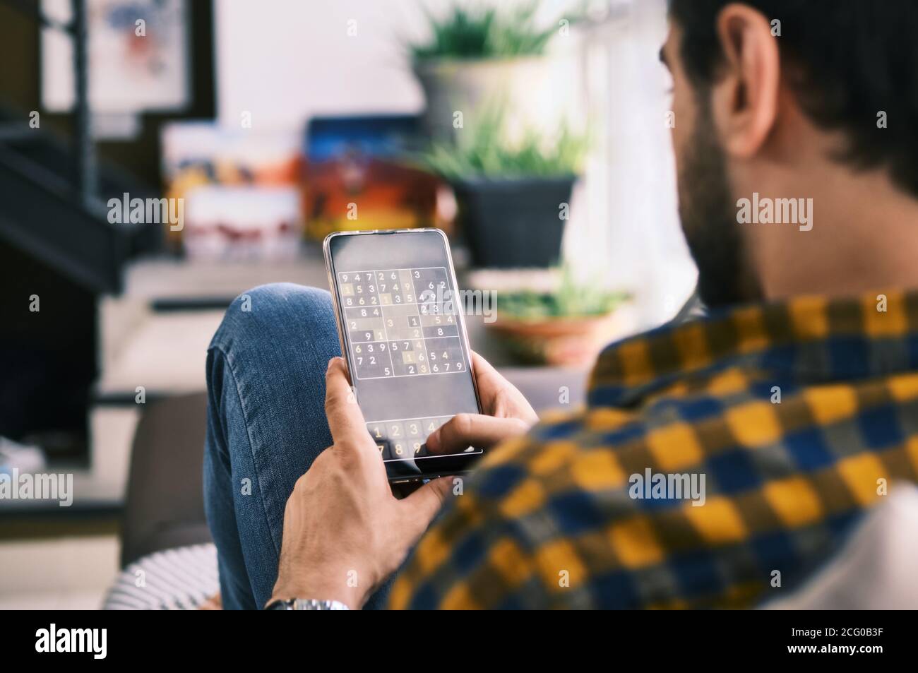 Gioco di Sudoku di Young Man con l'app sullo smartphone Foto Stock