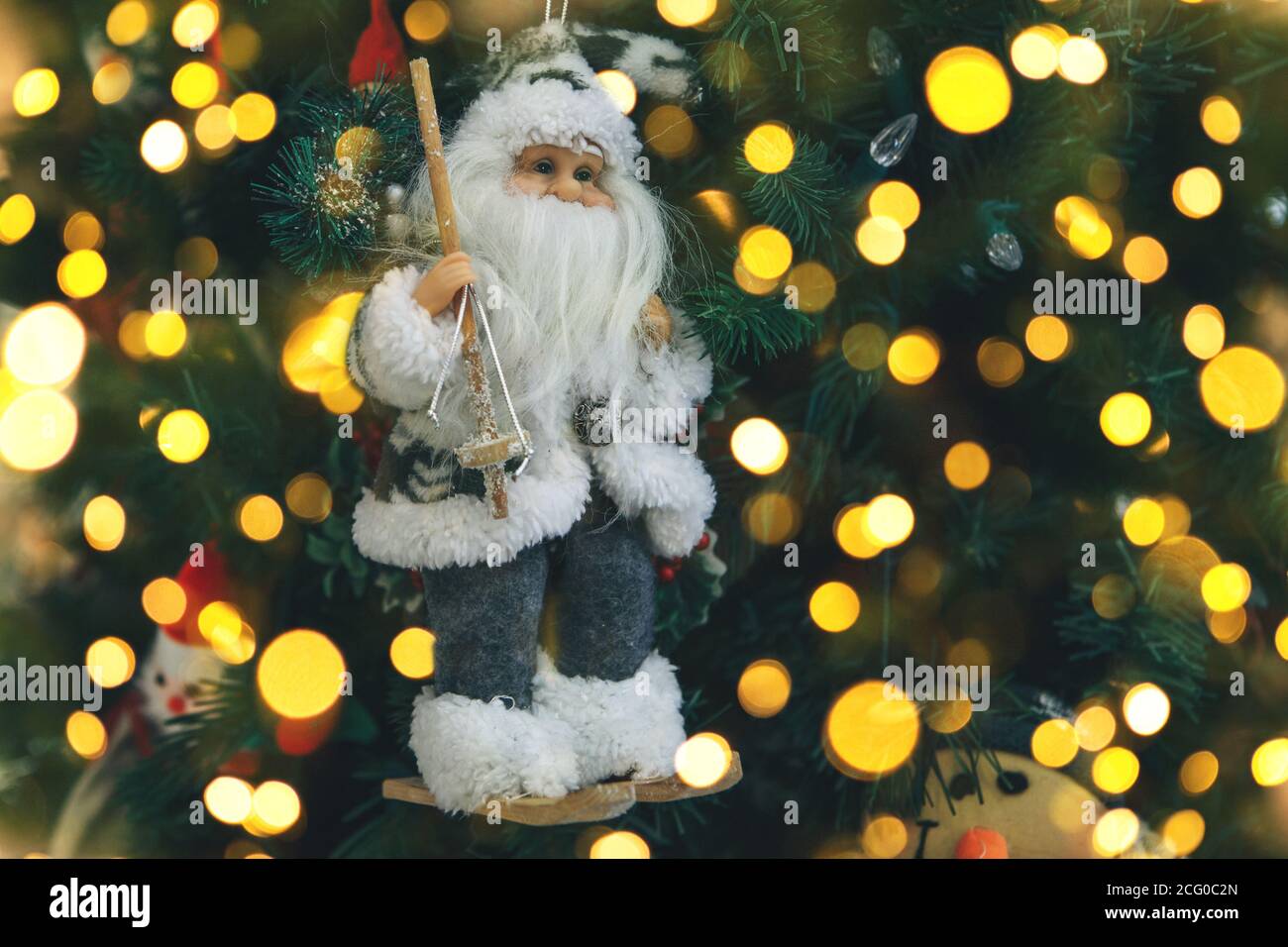 Primo piano del giocattolo di Natale di Babbo Natale sull'albero di Natale. Ci sono luci intorno. Foto Stock