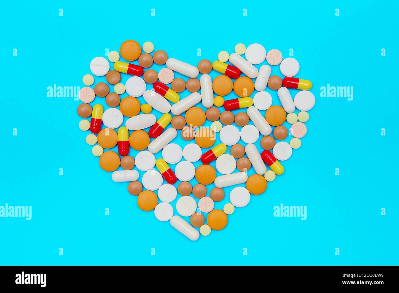 capsule di farmaci e pillole su sfondo blu. Pillole multicolore disposte a forma di cuore. Foto Stock