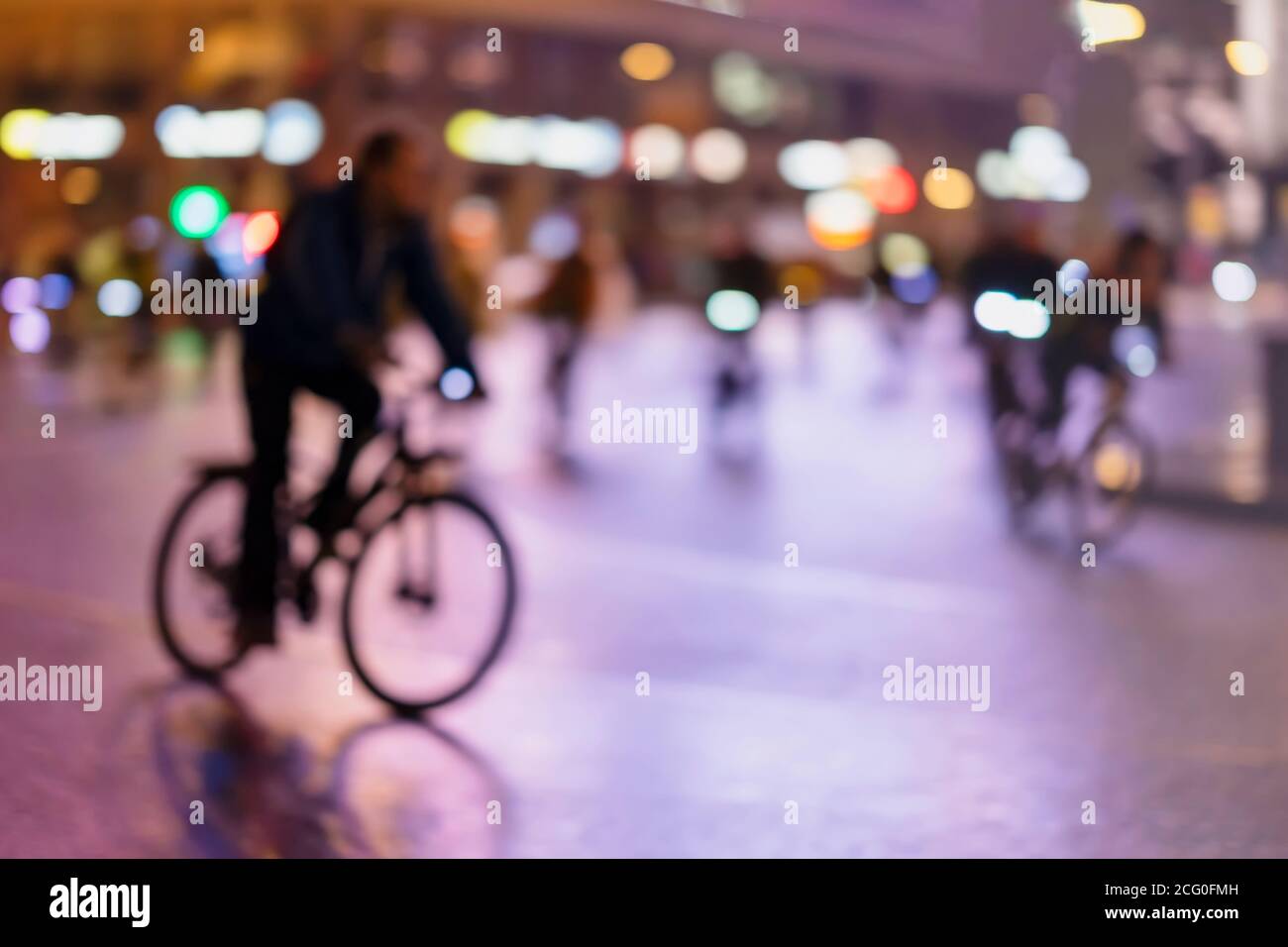 Sfondo di stile offuscato di silhouette di astratte persone irriconoscibili, bici da corsa, città notturna, bokeh illuminazione, sfocatura movimento. Stile di vita sano Foto Stock
