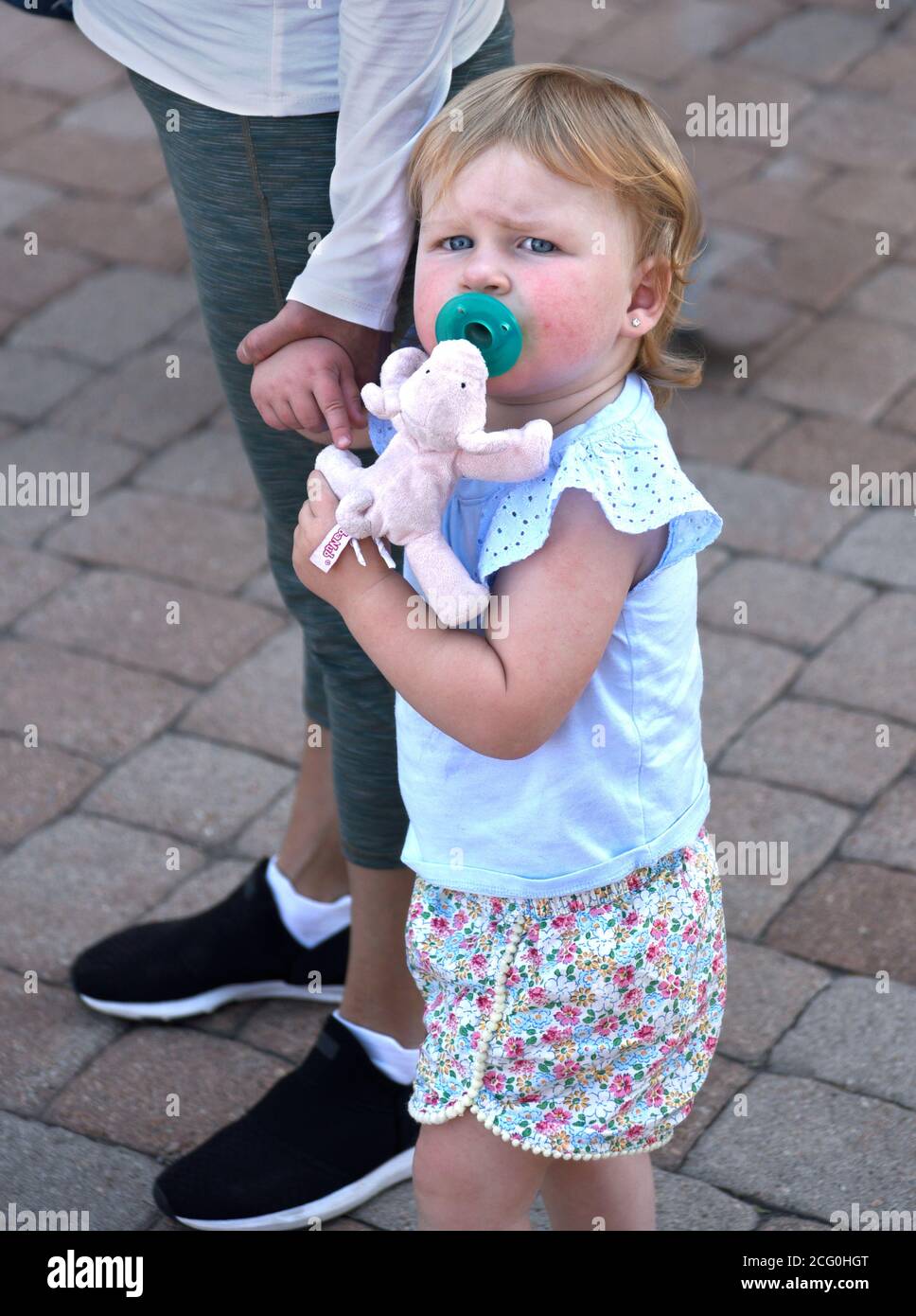Una giovane ragazza tiene la mano della madre e si aggrava ad un giocattolo mentre la famiglia visita Santa Fe, New Mexico. Foto Stock