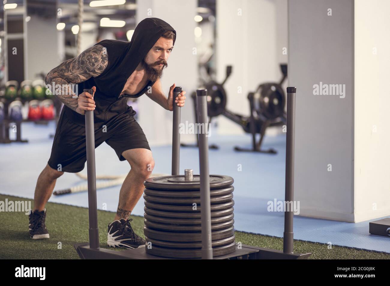 Giovane e forte che spinge l'attrezzatura di esercitazione a. la palestra Foto Stock