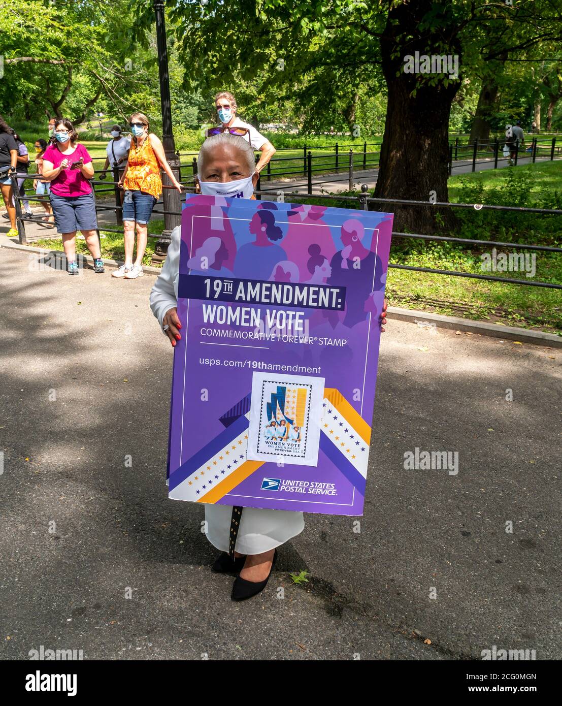 Un visitatore promuove il diciannovesimo Emendamento USPS, francobollo commemorativo al Women’s Rights Pioneer Monument on Literary Walk di Central Park a New York, il giorno della sua inaugurazione, mercoledì 26 agosto 2020. La statua, da sinistra a destra, della verità di soggiorno, Susan B. Anthony ed Elizabeth Cady Stanton commemora il 100° anniversario del diciannovesimo emendamento che ha dato alle donne il diritto di voto. Lo scultore è Meredith Bergmann ed è l'unico monumento del Central Park che raffigura donne reali. (© Richard B. Levine) Foto Stock