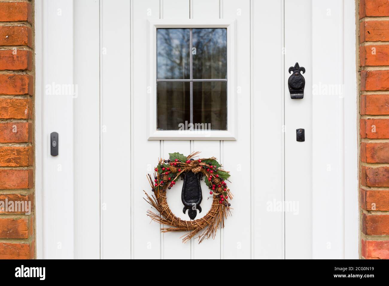 Dettaglio closeup di una porta in legno dipinta di bianco con corona di Natale. Inghilterra, Regno Unito Foto Stock