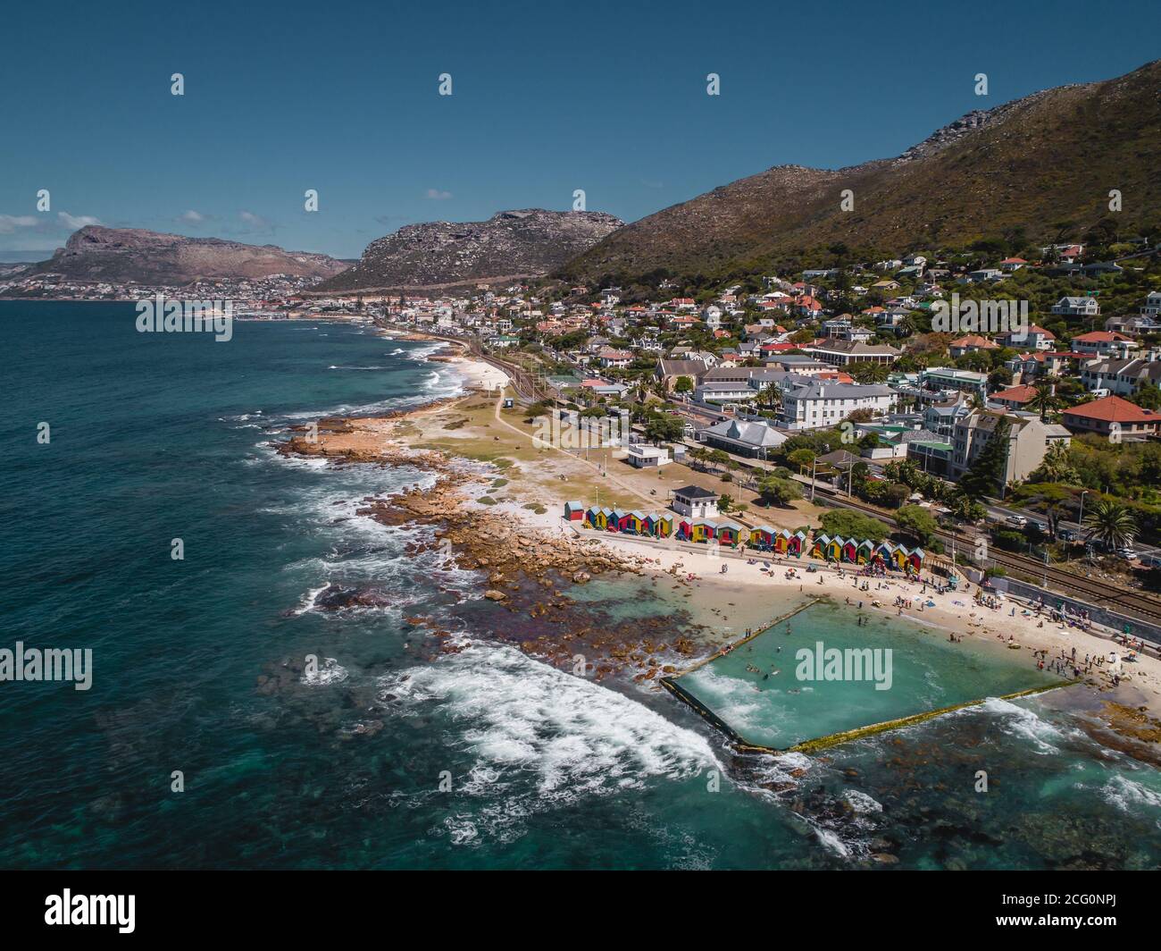 Belle e storicamente colorate capanne spiaggia di St James Beach e la piscina marea oceano con sfondo di montagna, Città del Capo, Sud Africa Foto Stock