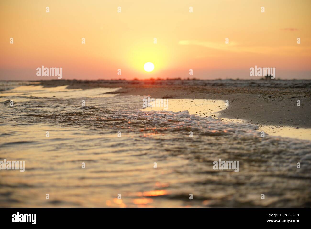 Tramonto sul mare. I raggi del sole si riflettono nella schiuma di mare Foto Stock