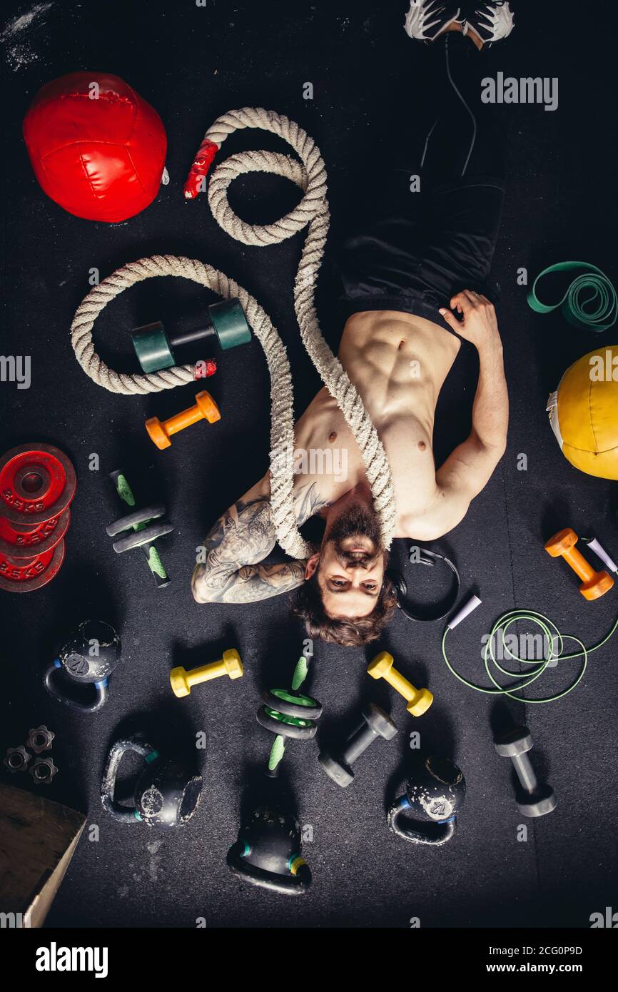 uomo sdraiato sul pavimento con una corda in palestra tra accessori per il  fitness e musica d'ascolto Foto stock - Alamy