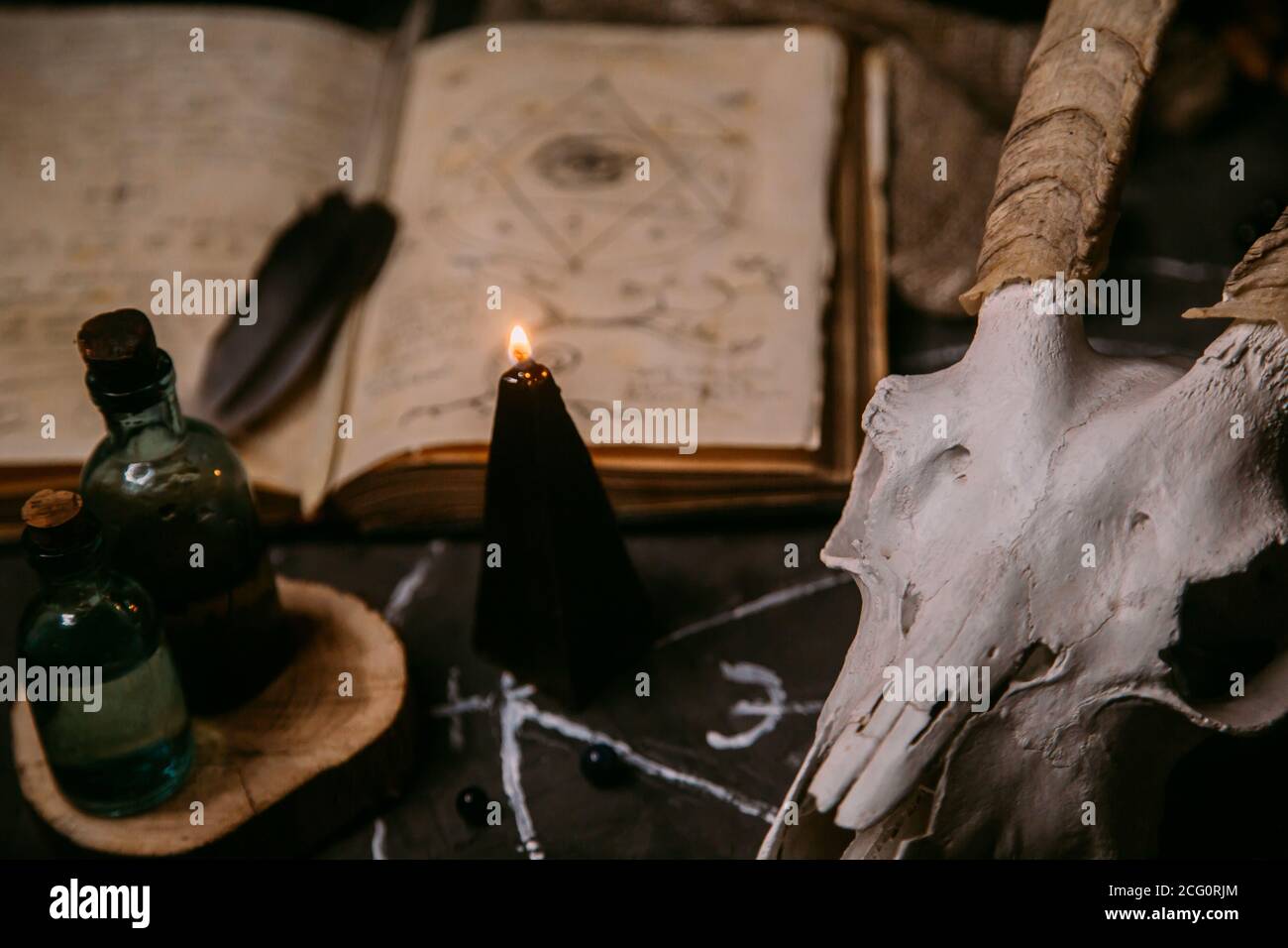 Gabbiano di capra bianco con corna, aprire il vecchio libro (testo - untraducibile, linguaggio immaginario), candele nere sul tavolo delle streghe. Occulto, esoterico, divinazione e. Foto Stock