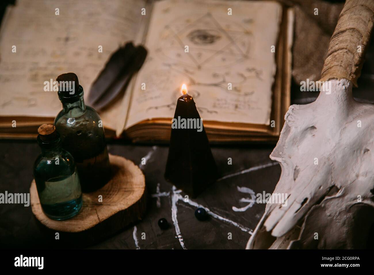 Gabbiano di capra bianco con corna, aprire il vecchio libro (testo - untraducibile, linguaggio immaginario), candele nere sul tavolo delle streghe. Occulto, esoterico, divinazione e. Foto Stock
