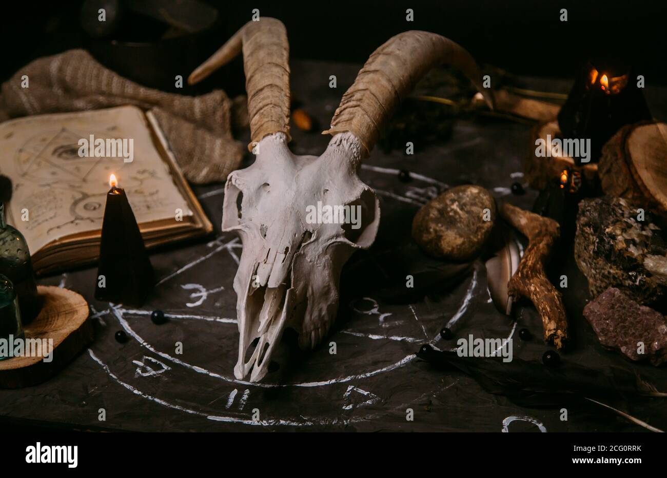 Gabbiano di capra bianco con corna, aprire il vecchio libro (testo - untraducibile, linguaggio immaginario), candele nere sul tavolo delle streghe. Occulto, esoterico, divinazione e. Foto Stock