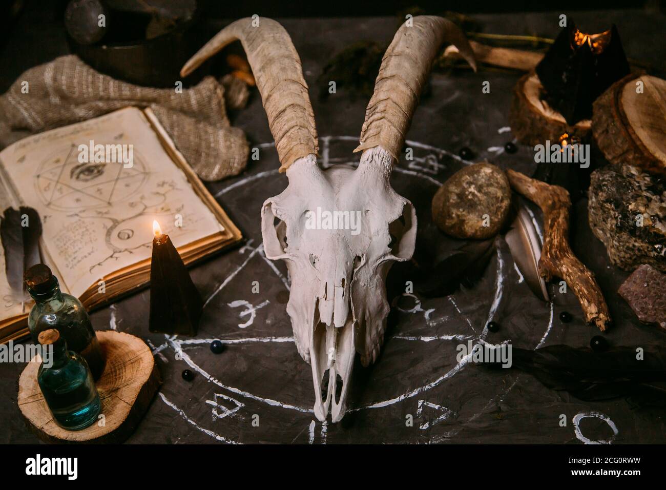 Gabbiano di capra bianco con corna, aprire il vecchio libro (testo - untraducibile, linguaggio immaginario), candele nere sul tavolo delle streghe. Occulto, esoterico, divinazione e. Foto Stock