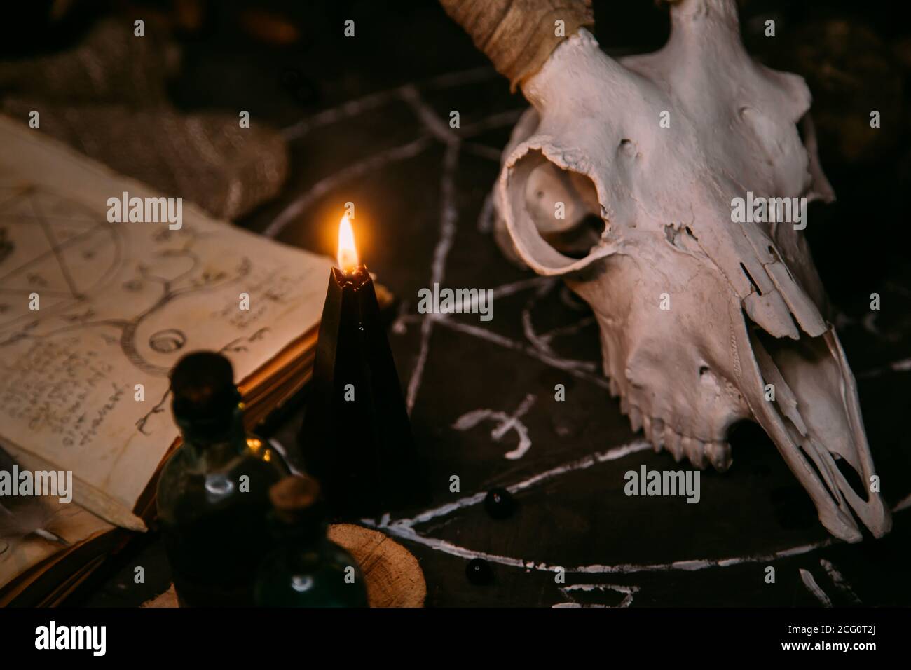 Gabbiano di capra bianco con corna, aprire il vecchio libro (testo - untraducibile, linguaggio immaginario), candele nere sul tavolo delle streghe. Occulto, esoterico, divinazione e. Foto Stock