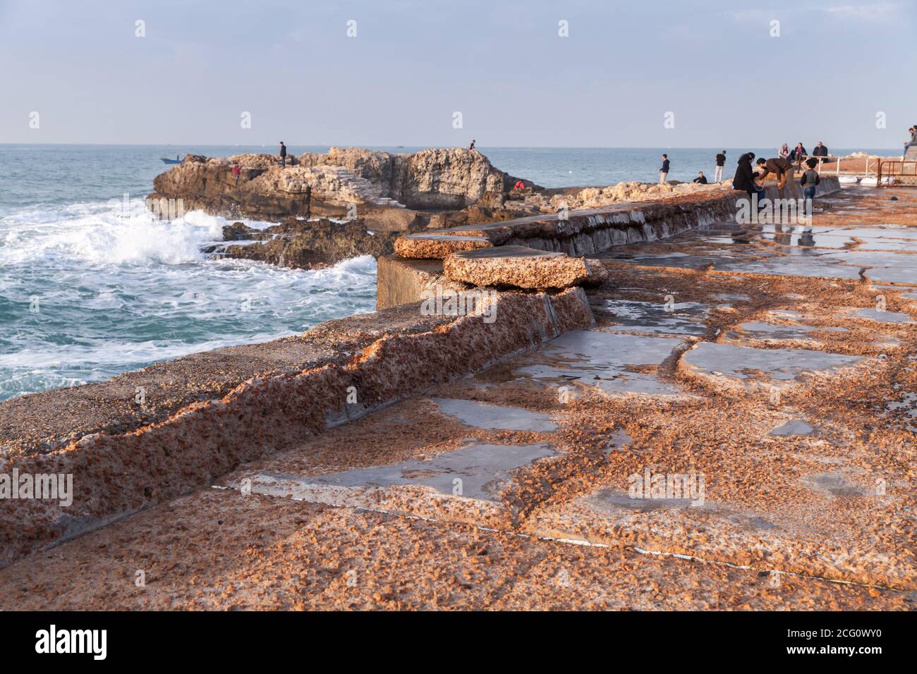 Alessandria, Egitto - 13 dicembre 2018: Paesaggio con rovinate fortificazioni costiere in pietra. La gente cammina sul molo Foto Stock