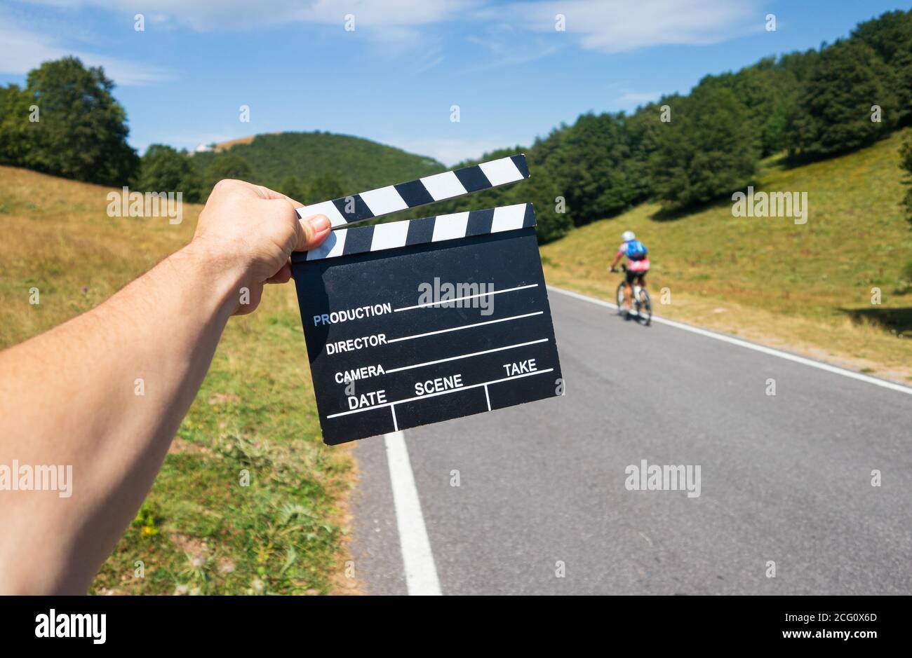 L'uomo tiene l'ardesia del film sulla natura verde colline paesaggio con un motociclista che fa sport all'aria aperta Foto Stock