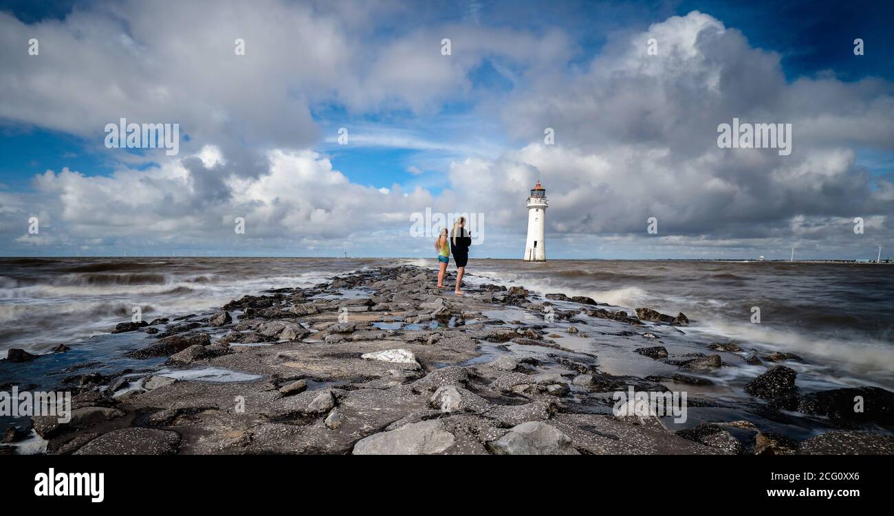Due ragazze che si levano in piedi sulla difesa del mare a roccia di Perch Sul Wirral Foto Stock