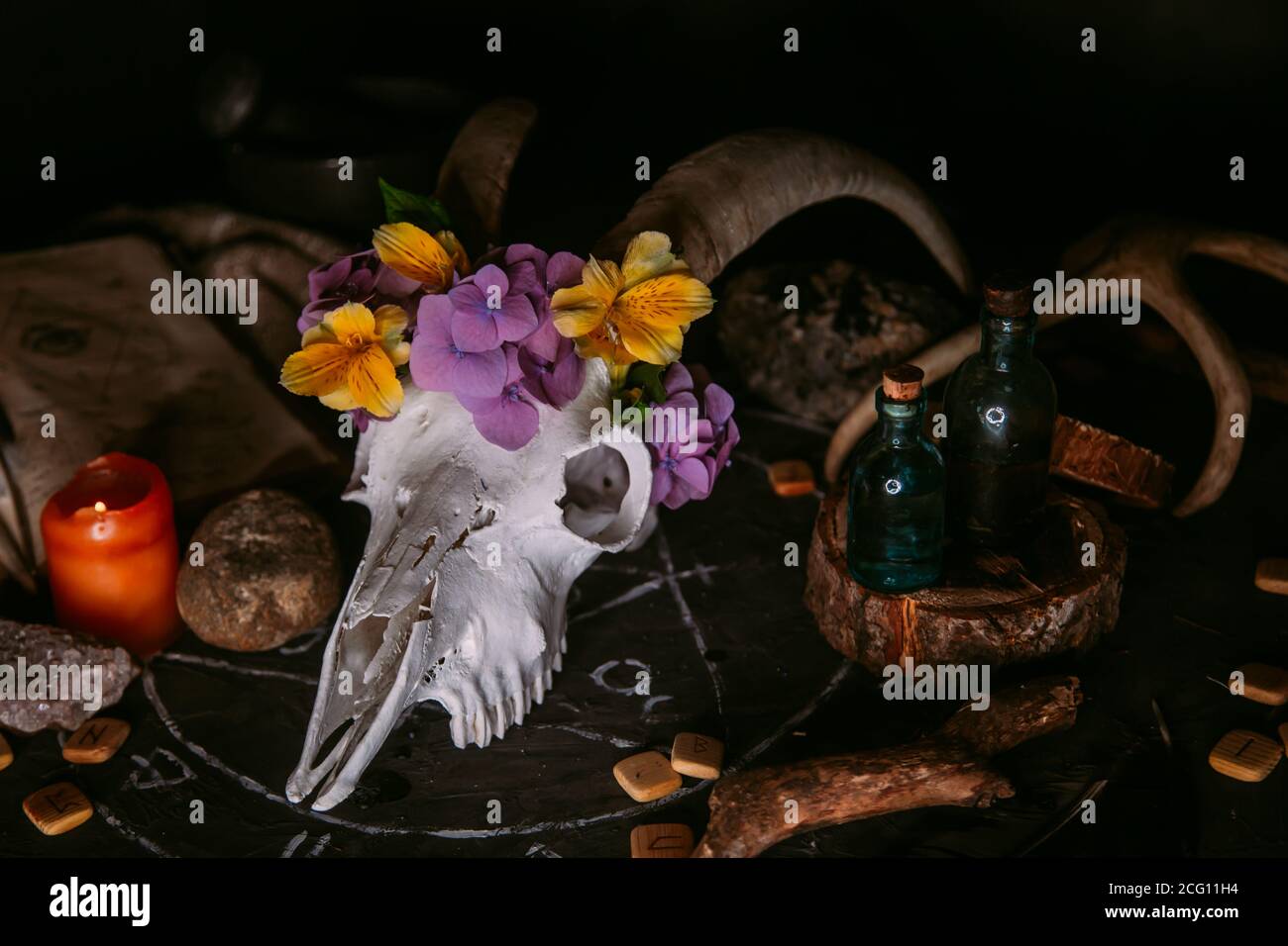 Gabbiano di capra bianco con corna, fiori, libro aperto vecchio, candele sul tavolo delle streghe. Concetto occulto, esoterico, divinazione e wicca. Halloween, giorno della dea Foto Stock