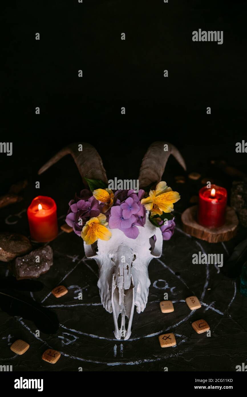 Gabbiano di capra bianco con corna, fiori, libro aperto vecchio, candele sul tavolo delle streghe. Concetto occulto, esoterico, divinazione e wicca. Halloween, giorno della dea Foto Stock