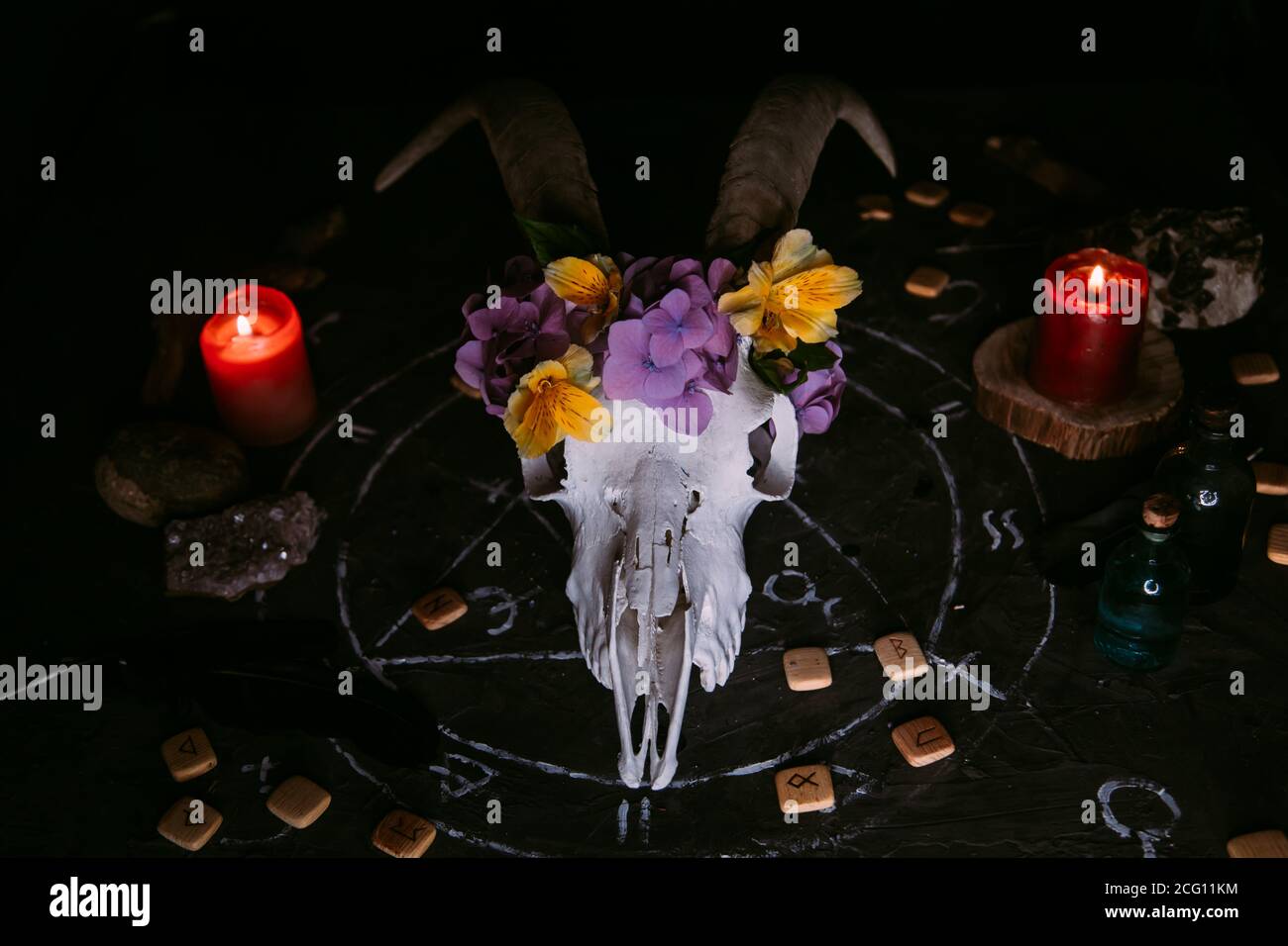 Gabbiano di capra bianco con corna, fiori, libro aperto vecchio, candele sul tavolo delle streghe. Concetto occulto, esoterico, divinazione e wicca. Halloween, giorno della dea Foto Stock