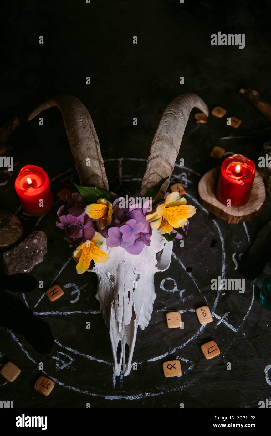 Gabbiano di capra bianco con corna, fiori, libro aperto vecchio, candele sul tavolo delle streghe. Concetto occulto, esoterico, divinazione e wicca. Halloween, giorno della dea Foto Stock