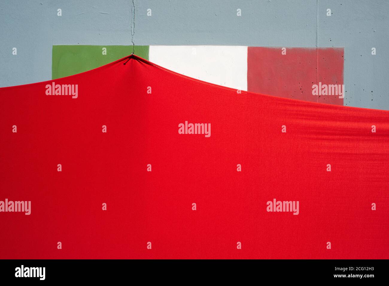 Una bandiera italiana dipinta su un muro con un rosso stoffa su di esso Foto Stock
