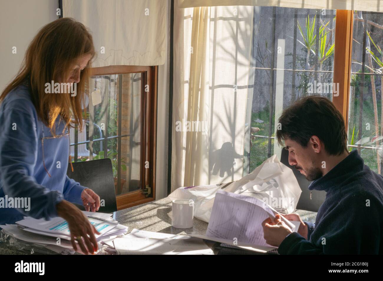 Giovane adulto uomo e donna adulta revisione della documentazione cartacea in ambiente luminoso Foto Stock