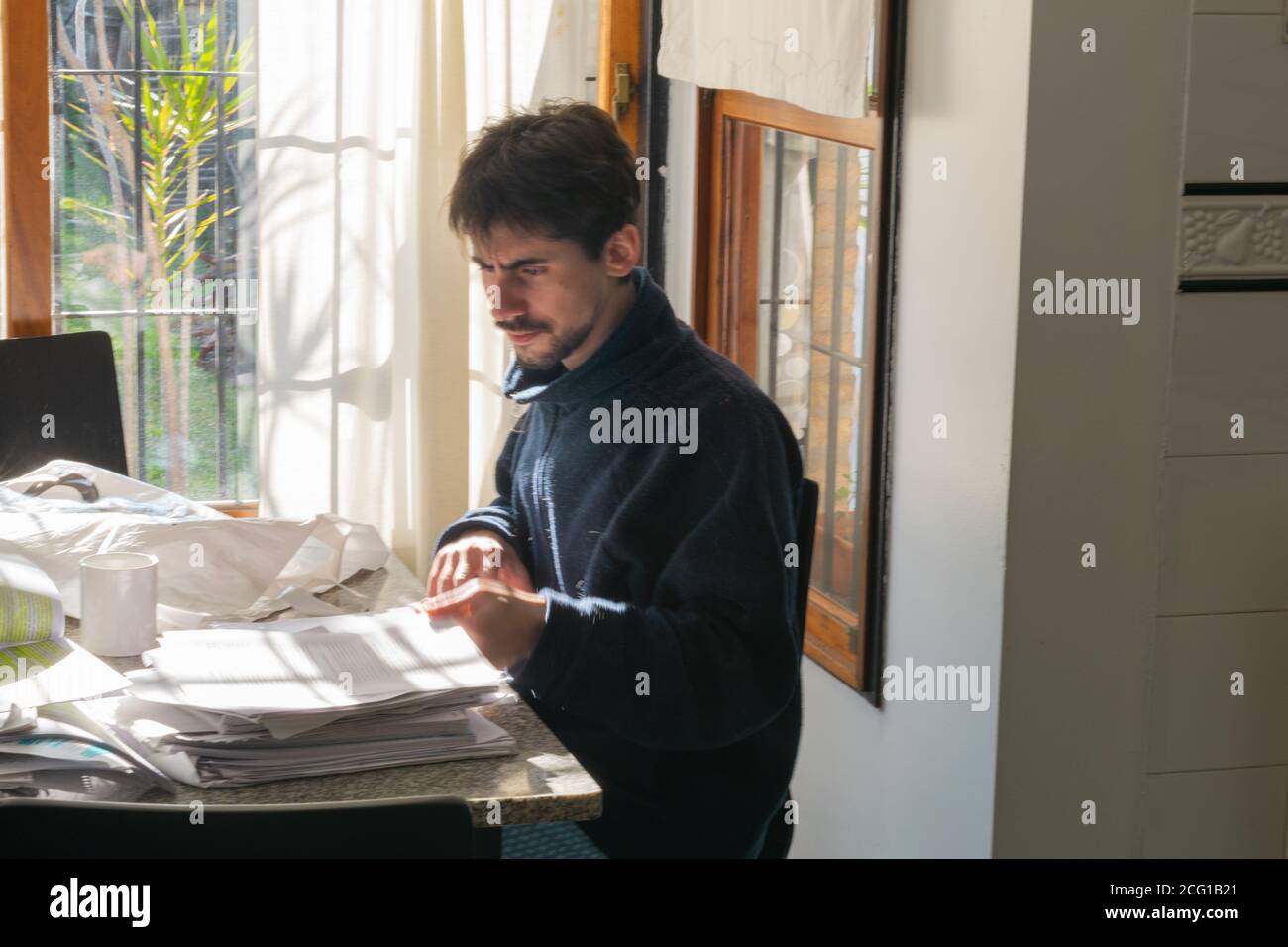 Giovane adulto che esamina la documentazione e le informazioni cartacee Foto Stock